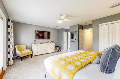 a bedroom with a yellow and white bed and a chair at Luxury home with private saltwater pool spa gazebo & deck - walk to beach in Santa Rosa Beach