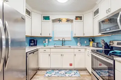 a kitchen with white cabinets and a stainless steel refrigerator at Luxury home with private saltwater pool spa gazebo & deck - walk to beach in Santa Rosa Beach