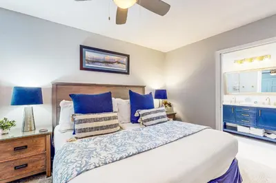 a bedroom with a bed with blue pillows and a window at Luxury home with private saltwater pool spa gazebo & deck - walk to beach in Santa Rosa Beach