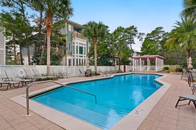 a large swimming pool with chairs and trees at Seagrove Serenity 4BR Coastal Retreat with Pool & Bikes in Santa Rosa Beach