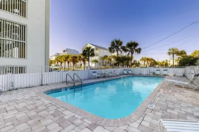 a swimming pool in front of a white fence at Fourth floor oceanfront condo with pool access ocean views and washer&dryer in Santa Rosa Beach