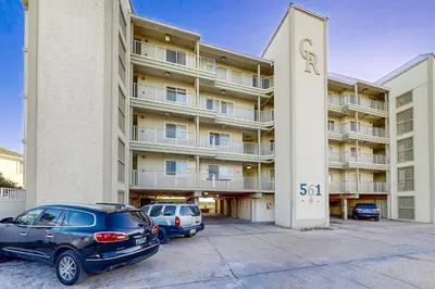 two cars parked in a parking lot in front of a building at Fourth floor oceanfront condo with pool access ocean views and washer&dryer in Santa Rosa Beach