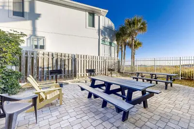 a picnic table and benches in front of a building at Fourth floor oceanfront condo with pool access ocean views and washer&dryer in Santa Rosa Beach