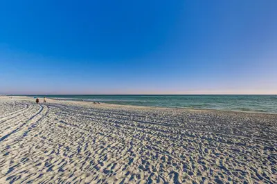 a beach with people walking on the sand and the ocean at Fourth floor oceanfront condo with pool access ocean views and washer&dryer in Santa Rosa Beach