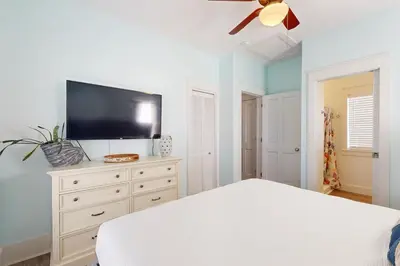 a bedroom with a white bed and a flat screen tv at Dog-friendly bungalow with on-site pool hot tub free WiFi and washer&dryer in Santa Rosa Beach