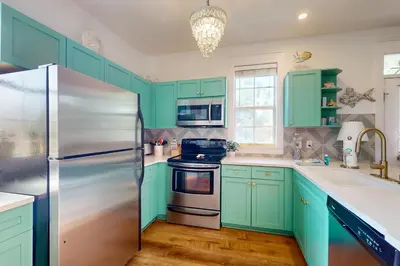 a kitchen with green cabinets and a stainless steel refrigerator at Dog-friendly bungalow with on-site pool hot tub free WiFi and washer&dryer in Santa Rosa Beach
