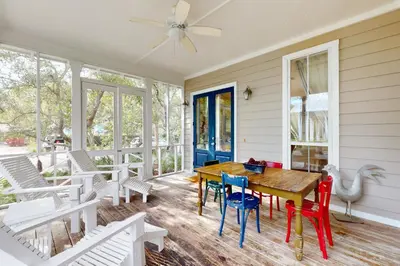 a screened porch with a wooden table and chairs at Coastal haven near the beach off scenic 30A with two pools & porch- dog-friendly in Santa Rosa Beach