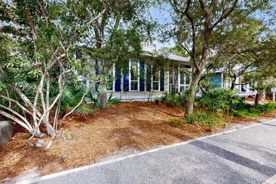 a house with trees in front of a yard at Coastal haven near the beach off scenic 30A with two pools & porch- dog-friendly in Santa Rosa Beach