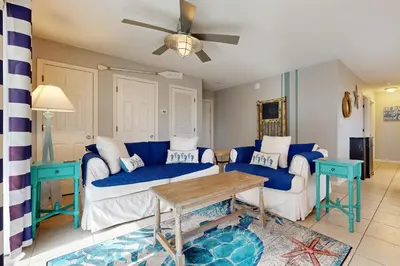 a living room with blue and white couches and a table at Seagrove Beach condo with AC pool & tennis - steps from the Gulf of Mexico in Santa Rosa Beach