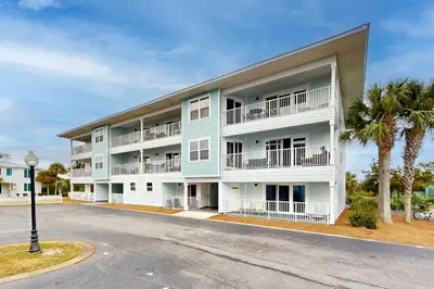 a blue and white apartment building with palm trees at Seagrove Beach condo with AC pool & tennis - steps from the Gulf of Mexico in Santa Rosa Beach