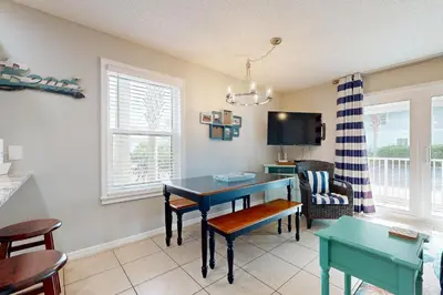 a living room with a table and chairs and a tv at Seagrove Beach condo with AC pool & tennis - steps from the Gulf of Mexico in Santa Rosa Beach