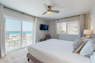 a bedroom with a bed and a balcony with the ocean at Delightful Beach Getaway with Water Views Beach Access Deck & Fast WiFi in Santa Rosa Beach