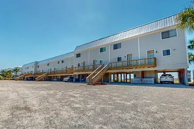 a large building with a staircase in a parking lot at Delightful Beach Getaway with Water Views Beach Access Deck & Fast WiFi in Santa Rosa Beach