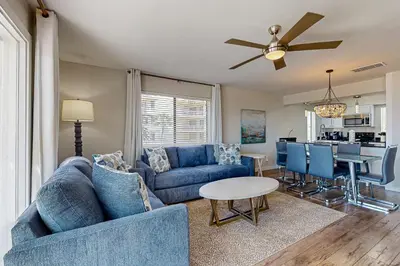 a living room with a blue couch and a table at Delightful Beach Getaway with Water Views Beach Access Deck & Fast WiFi in Santa Rosa Beach