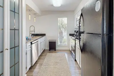 a kitchen with a black refrigerator and white cabinets at Delightful Beach Getaway with Water Views Beach Access Deck & Fast WiFi in Santa Rosa Beach