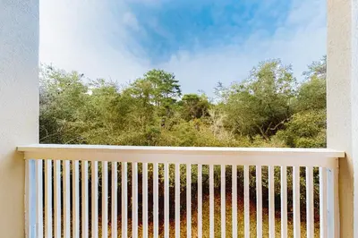 a balcony with a fence and trees in the background at Peaceful condo with pool access central AC and washer&dryer in Santa Rosa Beach