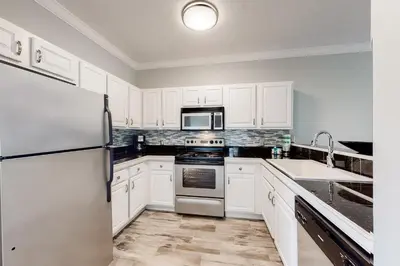 a kitchen with white cabinets and a stainless steel refrigerator at Peaceful condo with pool access central AC and washer&dryer in Santa Rosa Beach