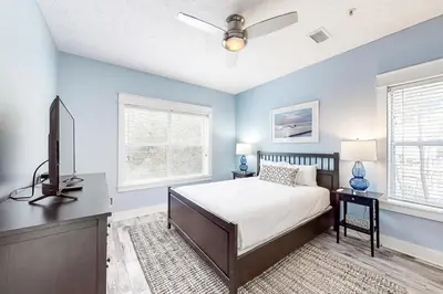 a bedroom with a bed and a flat screen tv at Peaceful condo with pool access central AC and washer&dryer in Santa Rosa Beach