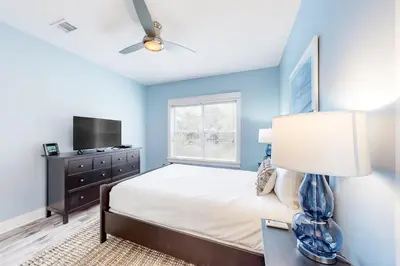 a bedroom with a bed with a lamp and a tv at Peaceful condo with pool access central AC and washer&dryer in Santa Rosa Beach