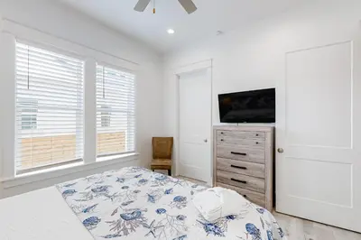 a bedroom with a bed and a tv and windows at Spacious open concept one story home with pool bikes grill and pet friendly in Santa Rosa Beach