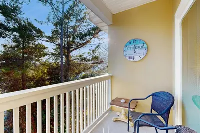 a porch with a blue chair and a clock on the wall at Third-floor condo with pool washer&dryer fast WiFi & central AC - near beach in Santa Rosa Beach