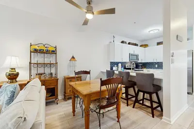 a kitchen and living room with a table and chairs at Third-floor condo with pool washer&dryer fast WiFi & central AC - near beach in Santa Rosa Beach