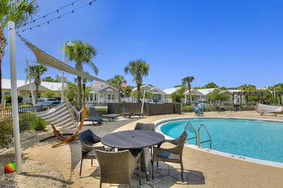 a patio with a table and chairs next to a pool at Dog-friendly home with pool patio & washer&dryer in Santa Rosa Beach