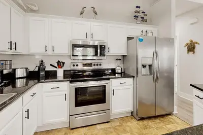a kitchen with white cabinets and a stainless steel refrigerator at Dog-friendly home with pool patio & washer&dryer in Santa Rosa Beach