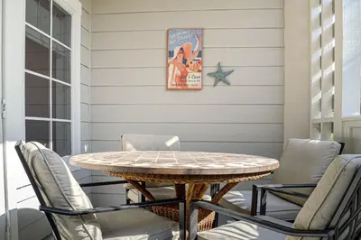 a patio with a table and chairs on a porch at 2nd-floor condo near beach with outdoor pool tennis balcony washer&dryer AC in Santa Rosa Beach