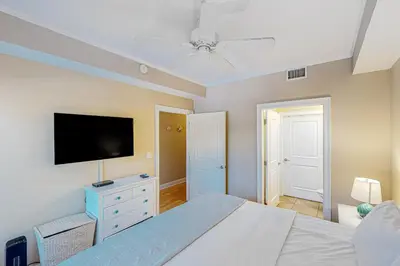 a bedroom with a bed and a flat screen tv at 2nd-floor condo near beach with outdoor pool tennis balcony washer&dryer AC in Santa Rosa Beach
