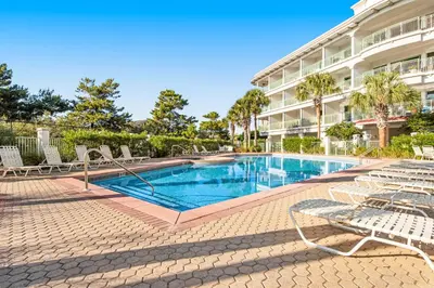 a swimming pool with chairs and a building at Comfortable studio with shared outdoor pool hot tub BBQ area and pool views in Seacrest