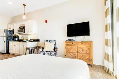 a bedroom with a bed and a kitchen with a refrigerator at Comfortable studio with shared outdoor pool hot tub BBQ area and pool views in Seacrest