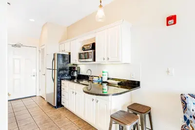 a kitchen with white cabinets and a black refrigerator at Comfortable studio with shared outdoor pool hot tub BBQ area and pool views in Seacrest