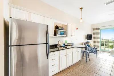 a kitchen with a stainless steel refrigerator and white cabinets at Comfortable studio with shared outdoor pool hot tub BBQ area and pool views in Seacrest