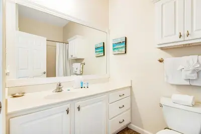 a white bathroom with a sink and a mirror at Comfortable studio with shared outdoor pool hot tub BBQ area and pool views in Seacrest