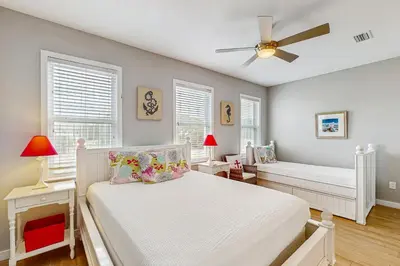 a white bedroom with a bed and a ceiling fan at Spacious Seabreeze Trail home with gulf views & shared pool - short walk to beach in Seacrest