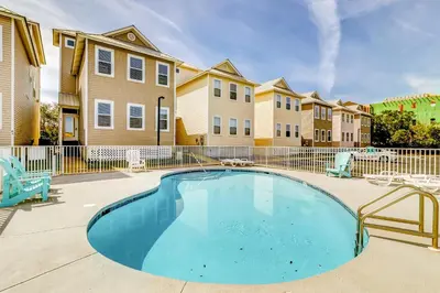 a swimming pool in a courtyard with chairs and condos at Spacious Seabreeze Trail home with gulf views & shared pool - short walk to beach in Seacrest