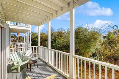 a white porch with two chairs and a pergola at Spacious Seabreeze Trail home with gulf views & shared pool - short walk to beach in Seacrest