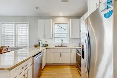 a kitchen with white cabinets and a stainless steel refrigerator at Spacious Seabreeze Trail home with gulf views & shared pool - short walk to beach in Seacrest
