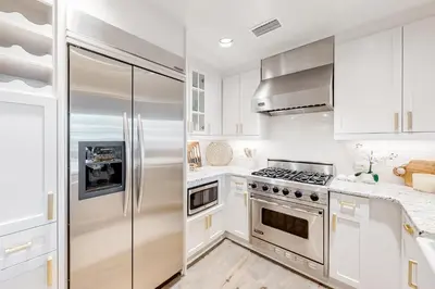 a kitchen with white cabinets and a stainless steel refrigerator at Gorgeous updated condo with balconies pool & great location near 30A in Watersound Beach