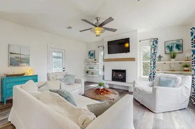 a living room with white furniture and a flat screen tv at Bright coastal getaway with plenty of room and simple beach entry in Inlet Beach