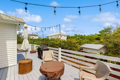 a deck with chairs and a table and lights at Bright coastal getaway with plenty of room and simple beach entry in Inlet Beach
