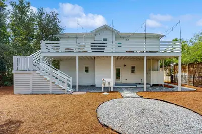 a white house with a staircase on it at Bright coastal getaway with plenty of room and simple beach entry in Inlet Beach
