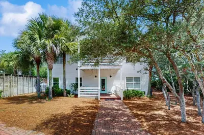 a white house with palm trees in front of it at Bright coastal getaway with plenty of room and simple beach entry in Inlet Beach
