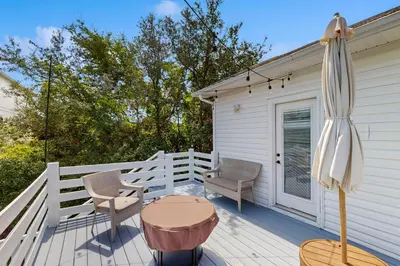 a patio with a table and chairs and an umbrella at Bright coastal getaway with plenty of room and simple beach entry in Inlet Beach