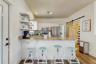 a kitchen with three stools at a counter at Bright coastal getaway with plenty of room and simple beach entry in Inlet Beach
