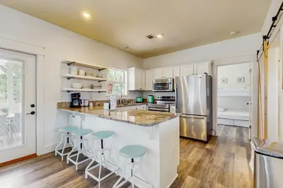 a kitchen with white cabinets and a counter with stools at Bright coastal getaway with plenty of room and simple beach entry in Inlet Beach