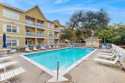 a swimming pool with lounge chairs and a building at Pool-view condo with private balcony washer and dryer Wifi in Santa Rosa Beach