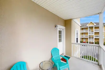 a balcony with two blue chairs and a balcony at Pool-view condo with private balcony washer and dryer Wifi in Santa Rosa Beach