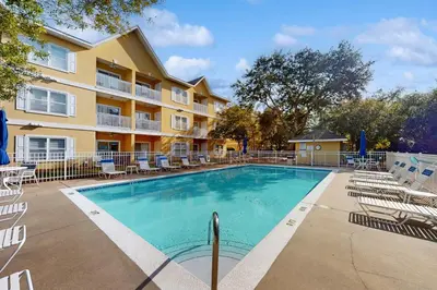 a swimming pool with chairs and a building at Pool-view condo with private balcony washer and dryer Wifi in Santa Rosa Beach